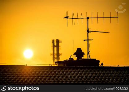 sunrise in in a city with house roof and antenna