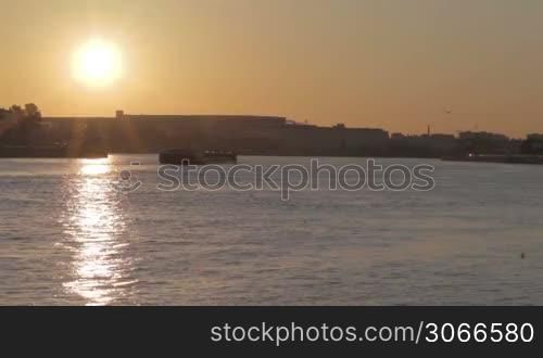 Sunrise in Saint Petersburg with sun reflection on water. Barge slowly moves.