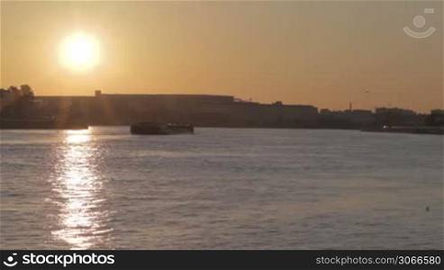 Sunrise in Saint Petersburg with sun reflection on water. Barge slowly moves.