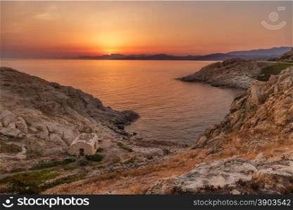 Sunrise in the bay at Ile Rousse in Corsica with an abandoned building in the foreground and Genoese tower and mountains of the desert des agriates in the background