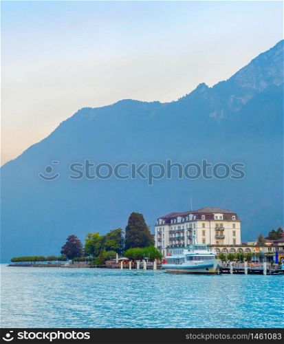 Sunrise landscape with resort embankment at mountain lake, moored touristic boats, Austria