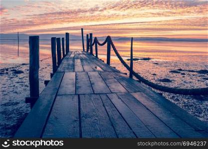 Sunrise of a wooden pier over a lake.