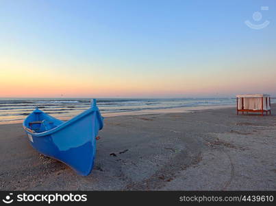 Sunrise on beach with blue boat