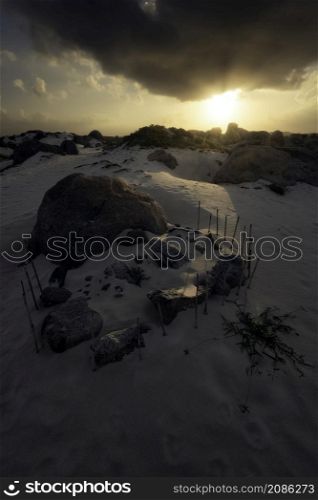 Sunrise on the Arashi Dunes on the northern tip of Aruba with a mysterious formation of sticks and stones on the dunes.