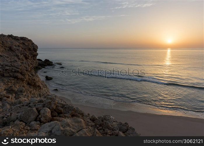Sunrise over cliffs and sea of Oman (Gulf of Oman) wild coast of Ras Al Jinz, Sultanate of Oman. Sunrise over the wild coast of Ras Al Jinz, Oman