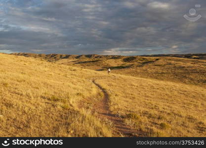 sunrise over Colorado prairie with a distant mountain biking figure - Soapstone Prairie Natural Area, Fort Collins