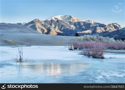 Sunrise over frozen Medano Creek with Sangre De Cristo Mountains in background, Great Sand Dunes National Park, Colorado