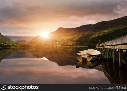 Sunrise over lake with boats moored at jetty