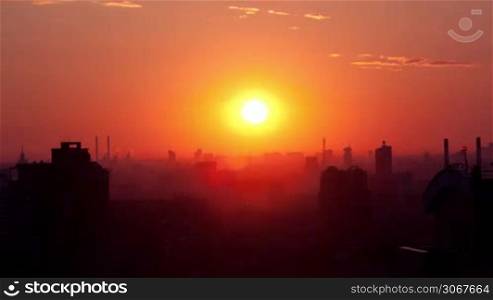 Sunrise over the city. Time lapse. High angle. Aerial view. The roofs of the houses lit by soft warm light