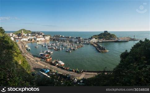 Sunrise over the tourist town of Ilfracombe in Devon. ILFRACOMBE, DEVON UK - JULY 24: Harbor at sunrise on 24 July 2017 in Ilfracombe, UK. The Damien Hirst statue Verity was erected in 2012. Sunrise over the tourist town of Ilfracombe in Devon