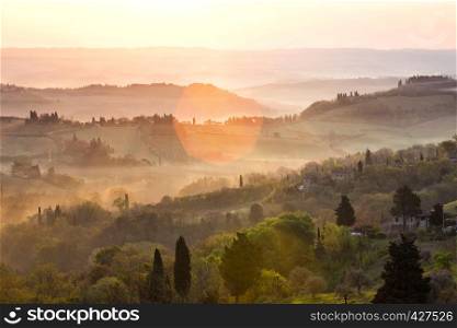 sunrise over tuscanian hills at the foggy morning. tuscany, italy