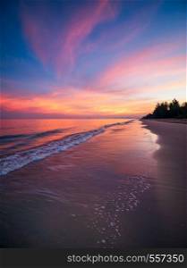 Sunrise with dramatic color sky over sea and beach with soft foam of water, Thailand