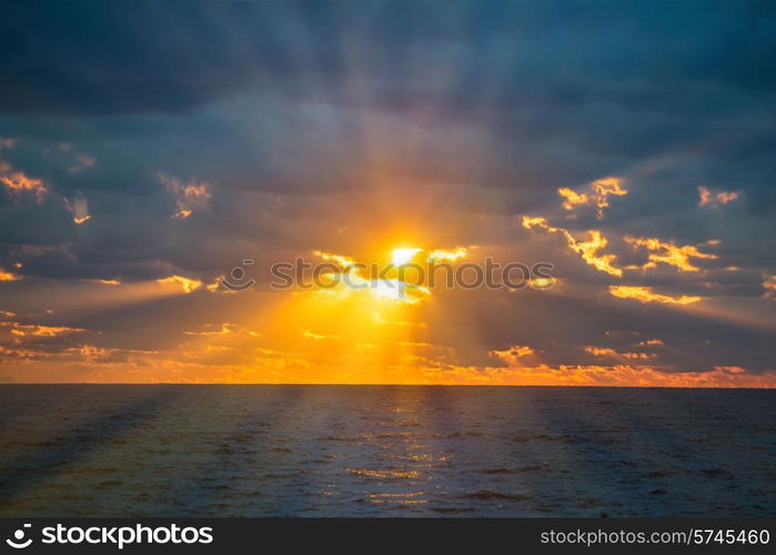 Sunset above sea, with waves, dramatic clouds on the sky