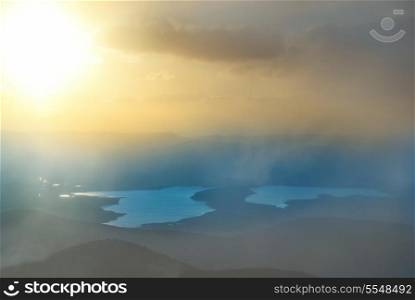 Sunset above the lake. Landscape with hills, clouds and sky.