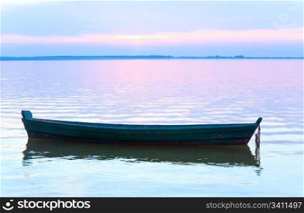 Sunset and old wooden fishing boat on summer lake bank (Svityaz, Ukraine)