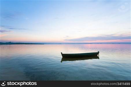 Sunset and old wooden fishing boat on summer lake bank (Svityaz, Ukraine)