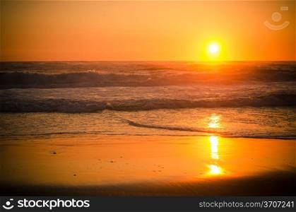 Sunset at a sandy beach with clear sky.