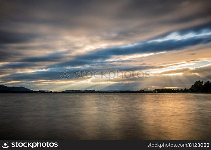 Sunset at Lake Constance with powerful cloudburst and sunbeams