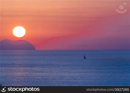 Sunset at sea with shipping boat silhouette.