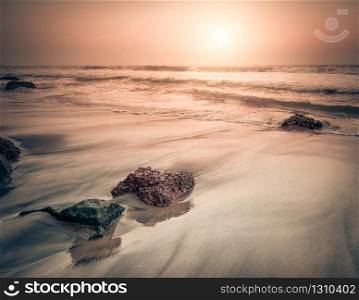 Sunset at tropical beach. Rocks at the ocean coast under evening sun. South India landscape