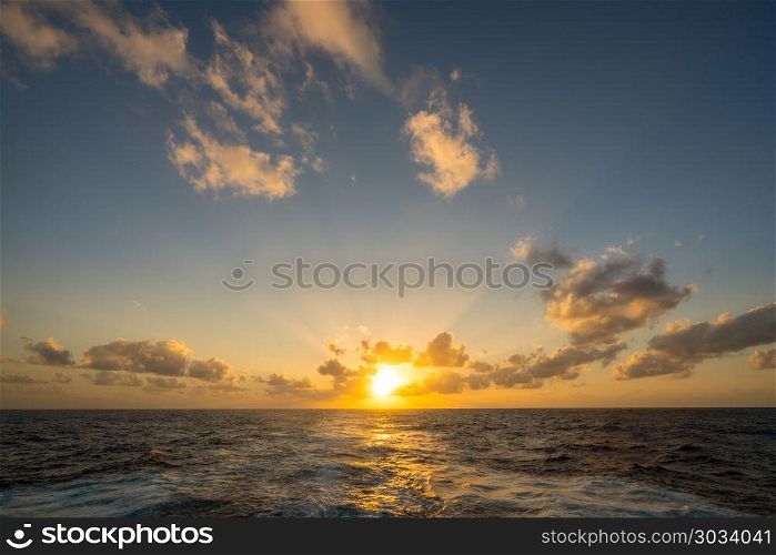 Sunset behind a cruising cruise ship at sea. Sunset over the wake of a cruise ship crossing the Atlantic. Sunset behind a cruising cruise ship at sea