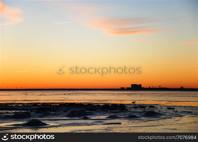 Sunset by the coast of the Baltic Sea with the skyline of the city Kalmar in the horizon
