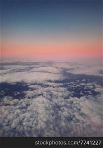 Sunset cloudscape, aerial view out of the plane window above the fluffy clouds. Tranquil sky evening scene, misty nebula. Air fresheners, celestial beauty, vertical background