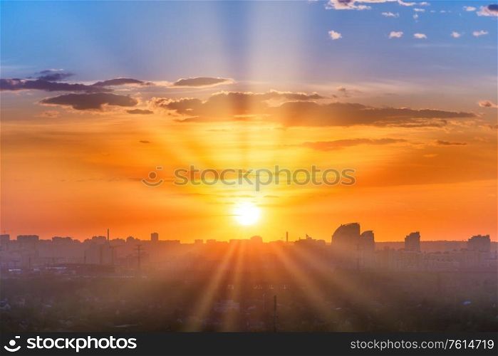 Sunset in big city, landscape with dramatic sky, clouds and sun rays