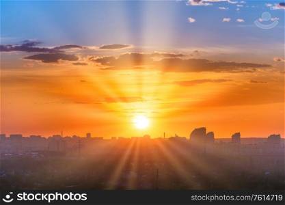 Sunset in big city, landscape with dramatic sky, clouds and sun rays