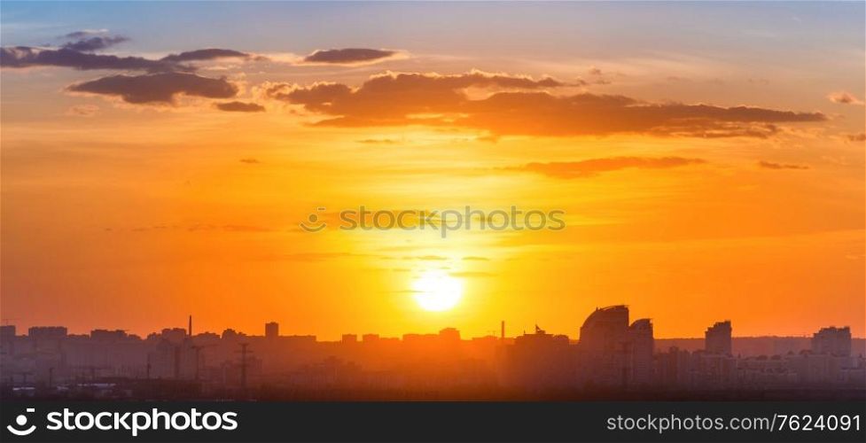 Sunset in big city, panorama ladscape with dramatic sky, clouds and sun rays