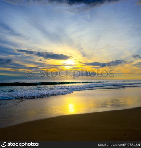 Sunset in ocean, sea waves and sand. Free space for text.