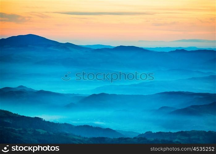 Sunset in the mountains. Dramatic colorful clouds over blue hills
