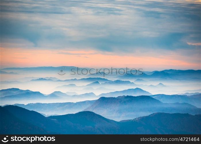 Sunset in the mountains. Dramatic colorful clouds over blue hills