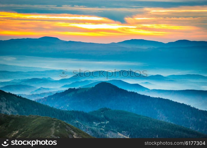 Sunset in the mountains. Dramatic colorful clouds over blue hills