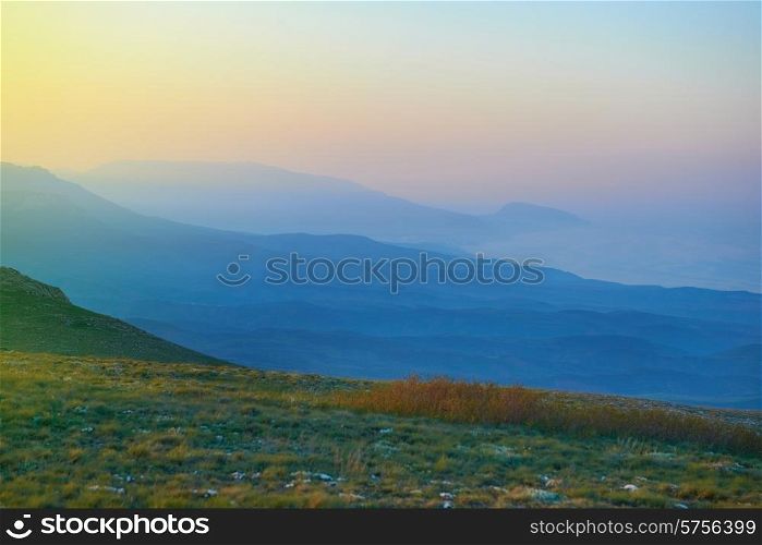 Sunset in the mountains. Sun and blue fog on background