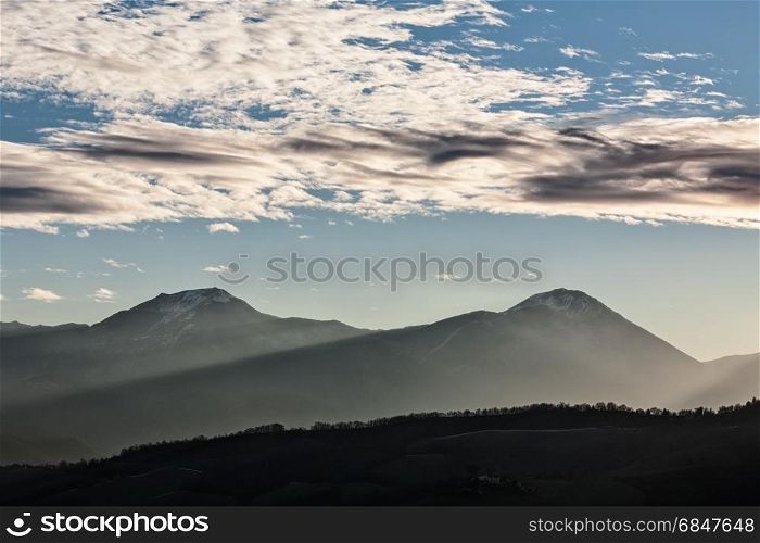 Sunset in the mountains with sunny beams and cloudy sky. Sunset in the mountains with sunny beams. Sunset in the mountains with sunny beams