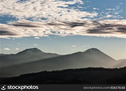 Sunset in the mountains with sunny beams and cloudy sky. Sunset in the mountains with sunny beams. Sunset in the mountains with sunny beams
