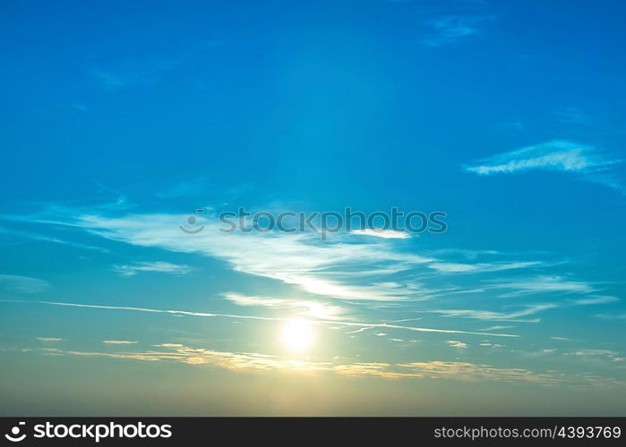 Sunset in the sky with blue marine clouds and big shining sun