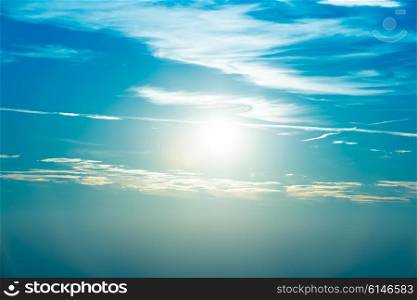 Sunset in the sky with blue marine clouds and big shining sun