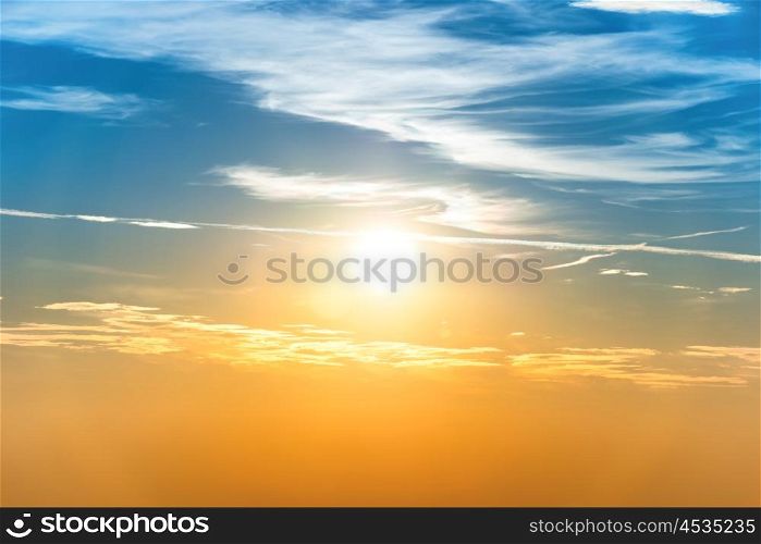 Sunset in the sky with blue orange clouds and big sun