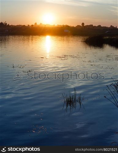 Sunset lake summer scenery with sun reflection.