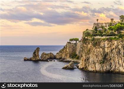 Sunset landscape on the sicilian coast farallones at the height of the town of tahormina italy