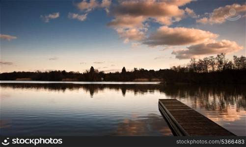 Sunset landscape over calm lake with reflections in water