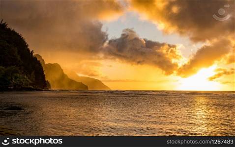 Sunset lights the receding cliffs of the NaPali coastline on north coast of Kauai in Hawaii. Sunset over the receding mountains of the Na Pali coast of Kauai in Hawaii