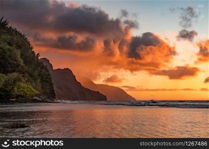 Sunset lights the receding cliffs of the NaPali coastline on north coast of Kauai in Hawaii. Sunset over the receding mountains of the Na Pali coast of Kauai in Hawaii