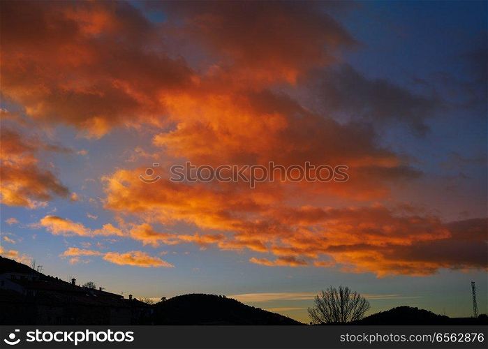 Sunset mountain silhouette with orange clouds on blue sky