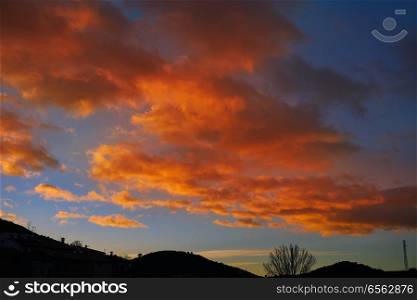Sunset mountain silhouette with orange clouds on blue sky