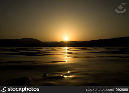 Sunset on a lake shore. Sun light reflections on water surface.