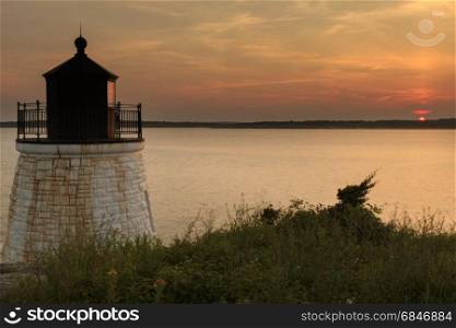 Sunset on a rocky shore.. Lighthouse on a rocky shore at sunset.