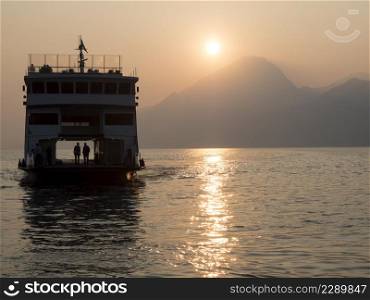 sunset on garda lake two men in a ferry boat